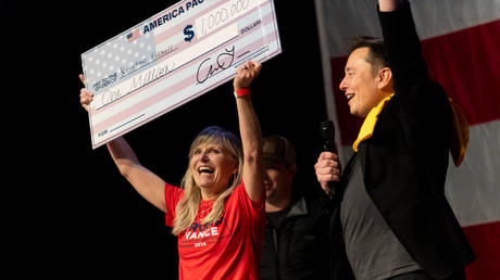 Musk awards Kristine Fishell with a $1 million check during a town hall at the Roxain Theater in Pittsburgh, Pennsylvania, October 20, 2024.