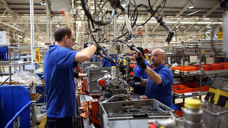 FILE PHOTO: An employee works on an engine production line at a Ford factory in Dagenham, England.