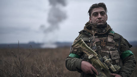 A Ukrainian soldier poses for a photo against the background of an explosion of a guided aerial bomb on the positions of Ukrainian soldiers on November 12, 2024 in Toretsk, Ukraine.