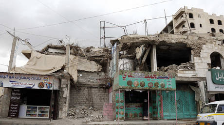 FILE PHOTO: A man buys from a shop located in a building destroyed in past aerial strikes in Sana'a, Yemen.