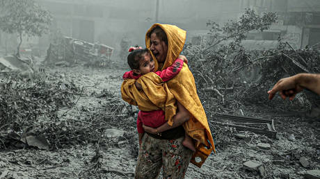 FILE PHOTO. A woman holding a girl reacts after Israeli airstrikes hit Ridwan neighborhood of Gaza City, Gaza.