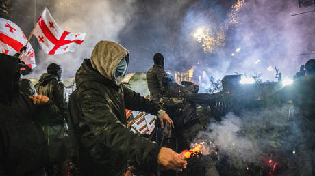 FILE PHOTO: A pro-European protester prepares to throw a firework at police from behind a makeshift barricade during an anti-government protest in Tbilisi, Georgia.