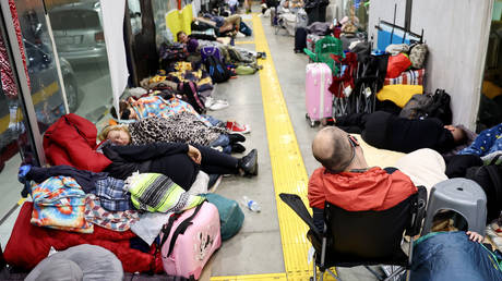 FILE PHOTO: Ukrainians who are seeking asylum in the US sleep as they await their turn to cross the border at a makeshift encampment in a bus stop near the US-Mexico border.