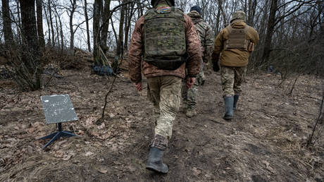 FILE PHOTO. Ukrainian servicemen walk past a Starlink satellite internet receiver.