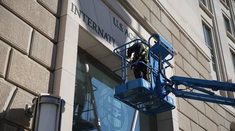 FILE PHOTO: A worker removes the USAID sign on the agency’s headquarters on February 07, 2025.