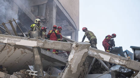 Iranian firefighters work at the scene of a destroyed residential building due to Israeli attacks in Tehran.