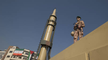 FILE PHOTO: An armed member of the Islamic Revolutionary Guard Corps (IRGC) stands next to an Iranian-made long-range surface-to-surface missile.