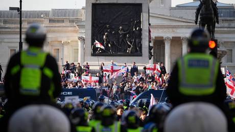 Metropolitan Police officers look toward protesters gathered in Trafalgar Square during the "Unite The Kingdom" rally on September 13, 2025 in London