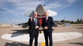 British Prime Minister Keir Starmer (L) and Defense Secretary John Healey stand in front of a Typhoon fighter jet at a Turkish airbase.