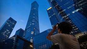 A passerby takes a photo of CITIC Tower after a light aircraft crashed into the skyscraper in Beijing, China, June 26, 2026.
