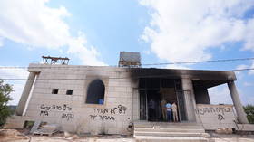 Hebrew graffiti targeting Palestinians is seen on the exterior walls of a burned mosque in the village of Qusra near Nablus in the West Bank, Palestine, on July 26, 2026.