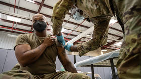 A US military medical specialist administers a Covid-19 vaccine shot to a soldier in Ford Knox.