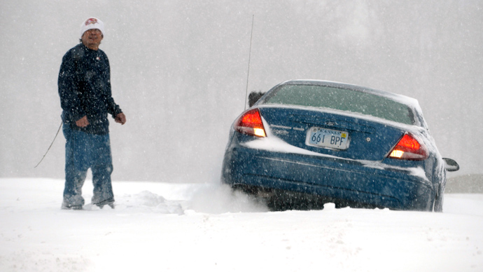 A man stands next to his car that is stuck in the snow during a blizzard in Kansas City, Kansas, February 21, 2013 (REUTERS / Dave Kaup)