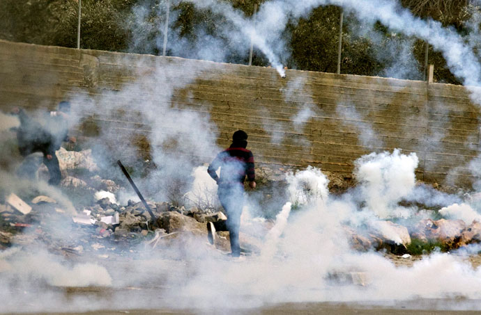 Palestinian protestors run for cover from tear gas fired by Israeli security forces during clashes next to Ofer prison, near the West Bank city of Ramallah, on February 22, 2013.(AFP Photo / Jack Guez)