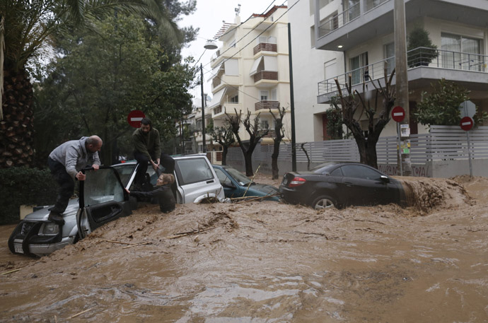 A woman is rescued from flood waters by a resident standing on top of her car during heavy rain in Chalandri suburb north of Athens February 22, 2013. (Reuters/John Kolesidis)