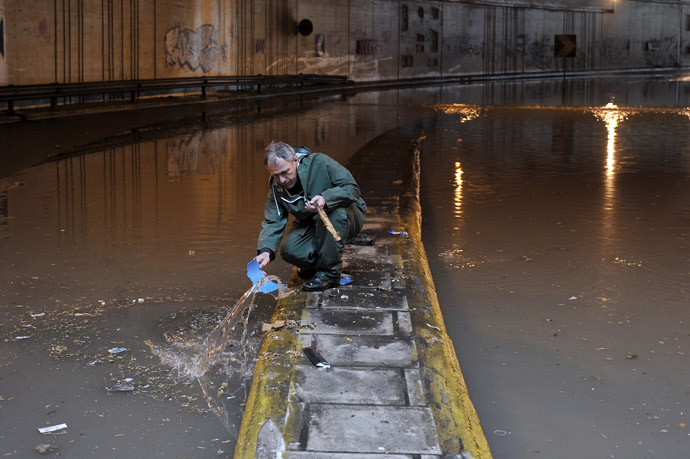 A municipality employee works at a flooded road in central Athens on February 22, 2013. (AFP Photo/Louisa Gouliamaki)