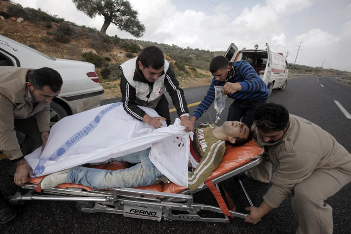 Palestinians paramedics aid a wounded protester following clashes with settlers in the West Bank village of Qusra near Nablus on February 23, 2013. (AFP Photo / Jaafar Ashtiyen)