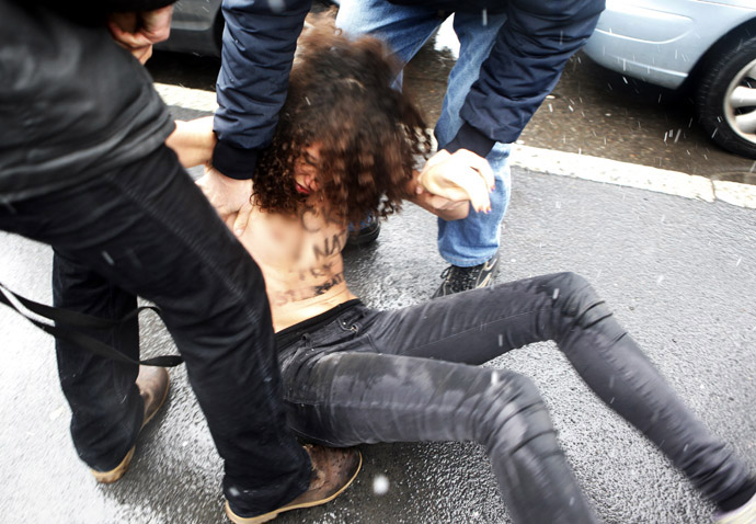 Police stop an activist from the women's rights organisation Femen during a protest outside the polling station where former Prime Minister Silvio Berlusconi cast his vote in Milan, February 24, 2013. Reuters/Cezaro De Luca) 