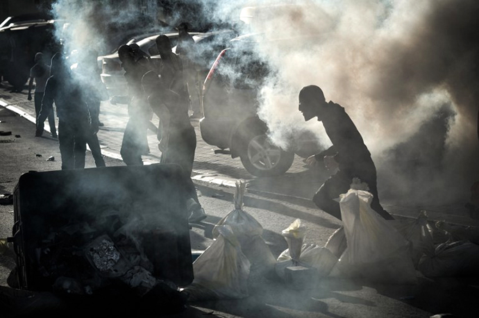 Bahraini protestors run for cover from tear gas fired by riot police during clashes with protestors, who tried to reach Salmaniya hospital to get the dead body of Mahmud al-Jaziri, on February 25, 2013. (AFP Photo / Mohammed Al-Shaikh)