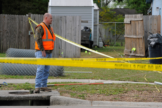 A crew member from the Hillsborough County Public Works Department sends a special pipe camera down a drain within the secured area surrounding a home where a sinkhole opened up and swallowed a man in Seffner, Florida, March 1, 2013 (Reuters / Brian Blanco)