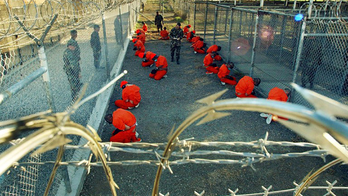 Detainees in orange jumpsuits sit in a holding area under the surveillence of US military police at Camp X-Ray at Naval Base Guantanamo Bay, Cuba. (AFP Photo / Shane T. Mccoy)