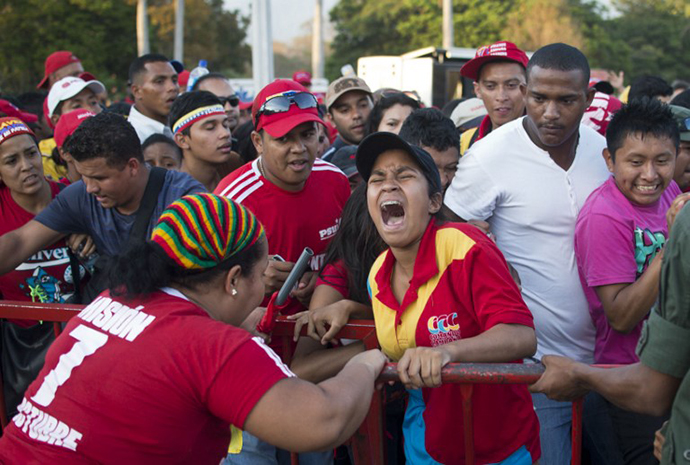 Guards keep supporters behind a fence as they wait to pay respects to late Venezuelan President Hugo Chavez. (AFP Photo / Ronaldo Schemidt)