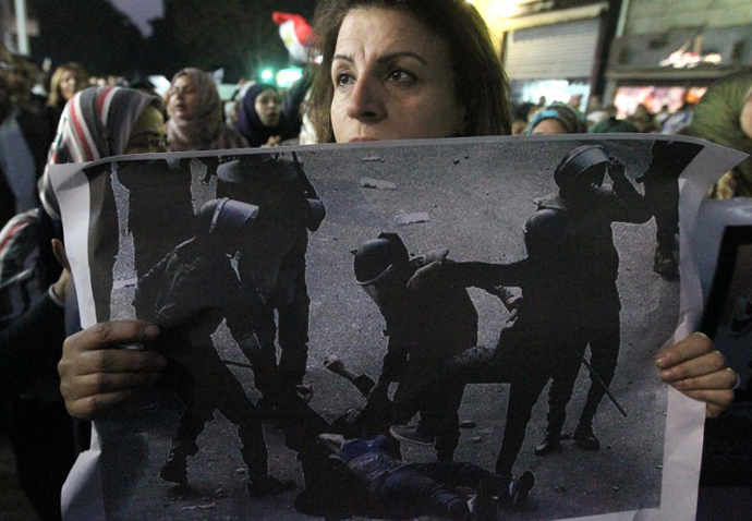 An Egyptian woman holds the widespread picture of a woman who was stripped and beaten by military police during clashes last week as Egyptians gather for a protest in downtown Cairo. (AFP Photo / Khaled Desouki)