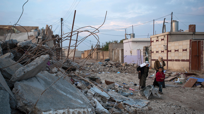Residents pass by buildings destroyed in a regime's bombardment in Ras al-Ain (AFP Photo / Giulio Petrocco)