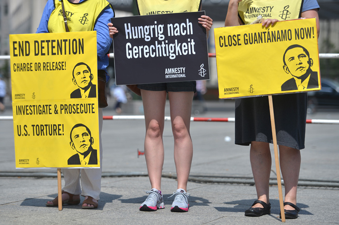 Activists from Amnesty International human rights association hold posters reading "End Detention Charge or Release", "Close Guantanamo Now" and displaying a drawing featuring US President Barack Obama during a protest action on the Potsdamer Platz in Berlin, on June 19, 2013 (AFP Photo / Oliver Lang) 