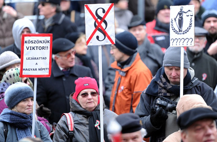 Participants carry placards reading (at left) 'Thank you Viktor! (referring toHungarian PM Viktor Orban) You discredited the Hungarian people!'. (AFP Photo / Attila Kisbenedek)