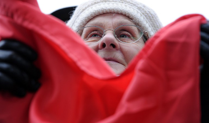 An elderly woman holds an Hungarian flag as she takes part in a demonstration on March 17, 2013. (AFP Photo / Attila Kisbenedek)
