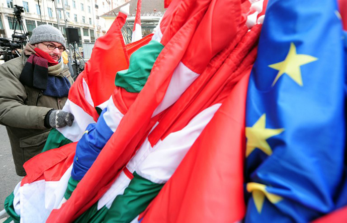A prepares Hungarian and European flags as he takes part in a demonstration on March 17, 2013. (AFP Photo / Attila Kisbenedek)