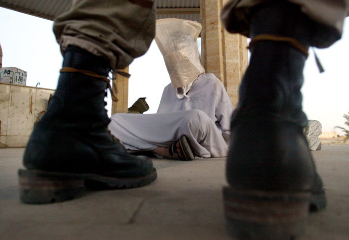 A U.S.soldier of the 1st Battalion (22nd regiment) of the fourth Division of the U.S. army stands guard next to detained Iraqis caught during a raid in Tikrit, September 10, 2003 (Reuters / Arko Datta)