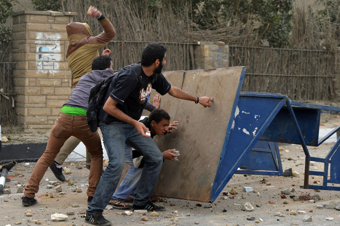 Egyptian protesters take cover during clashes with members of the Muslim Brotherhood near the movements' headquarters in Cairo on March 22, 2013. (AFP Photo / Haled Desouki)