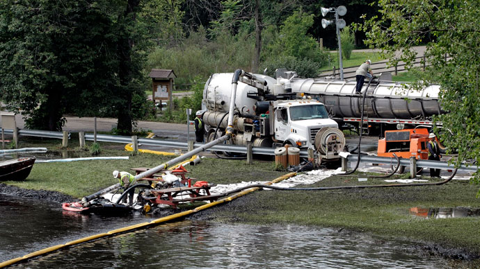 Workers using suction hoses try to clean up an oil spill of approximately 800,000 gallons of crude oil from the Kalamazoo River July 28, 2010 in Battle Creek, Michigan.(AFP Photo / Bill Pugliano)