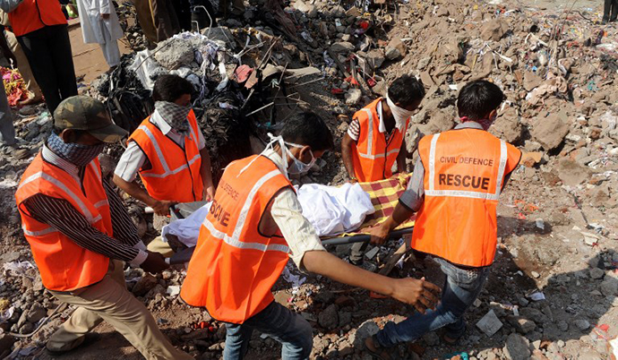 Resue officials and disaster management staff bring out a body from under the rubble and debris at the site of a building collapse at Mumbra in Thane, on the outskirts of Mumbai on April 6, 2013. (AFP Photo / Indranil Mukherjee)