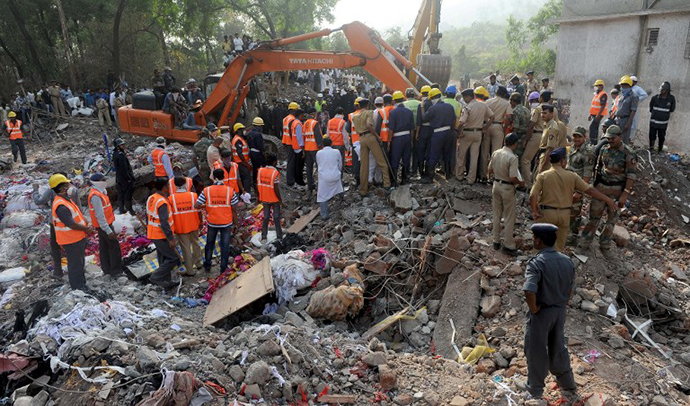 Resue officials and disaster management staff stand on top of the rubble and debris at the site of a building collapse at Mumbra in Thane, on the outskirts of Mumbai on April 6, 2013. (AFP Photo / Indranil Mukherjee)