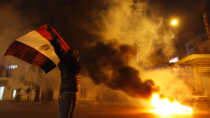 An anti-Mursi protester stands with the national flag and shouts slogan near a fire by protesters and tear gas released by riot police during clashes in front of the High Court in Cairo April 6, 2013.(Reuters / Amr Abdallah Dalsh)