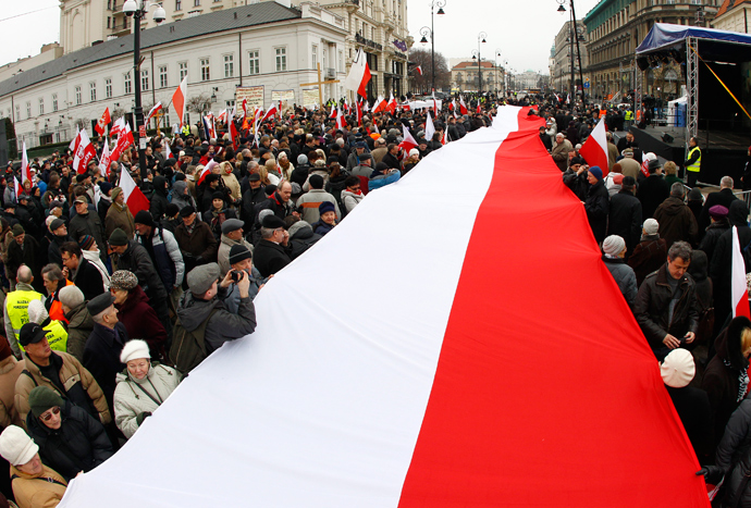 People hold a Polish flag during a remembrance ceremony for the 2010 plane crash that killed former Polish President Lech Kaczynski and 95 others outside of the Presidential Palace in Warsaw April 10, 2013 (Reuters / Peter Andrews) 