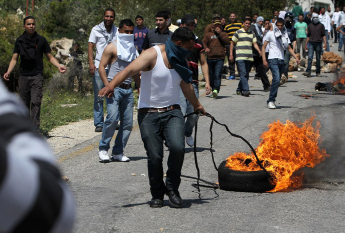 A Palestinian pulls a tyre in fire during clashes with Israeli forces following a protest against the expropriation of Palestinian land by Israel in the West Bank village of Silwad, east of Ramallah, on April 12, 2013. (AFP Photo / Abbas Momani)