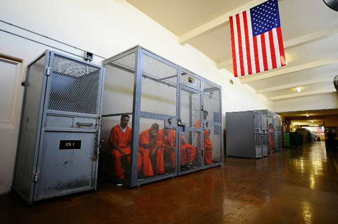 Inmates at Chino State Prison sit inside a metal cage in the hallway in Chino, California. (AFP Photo / Kevork Djansezian)