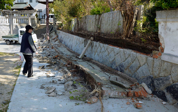 A woman walks past collapsed stone wall at a shrine after an earthquake in Sumoto, Hyogo prefecture, western Japan, in this photo taken by Kyodo April 13, 2013 (Reuters / Kyodo)