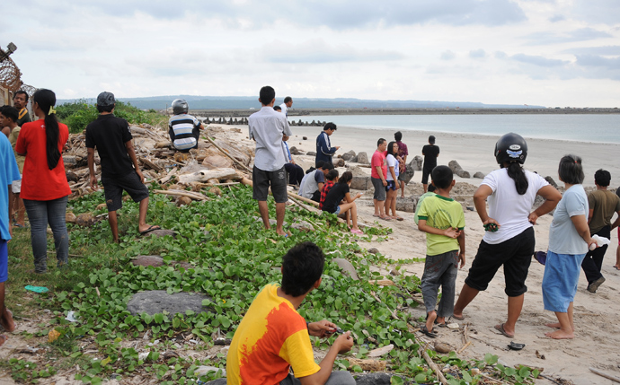 Local residents stand outside the fence at Bali's international airport near Denpasar, looking out at the end of the runway (in background), after news that a Lion Air plane missed the runway on April 13, 2013 (AFP Photo / Sonny Tumbilaka)