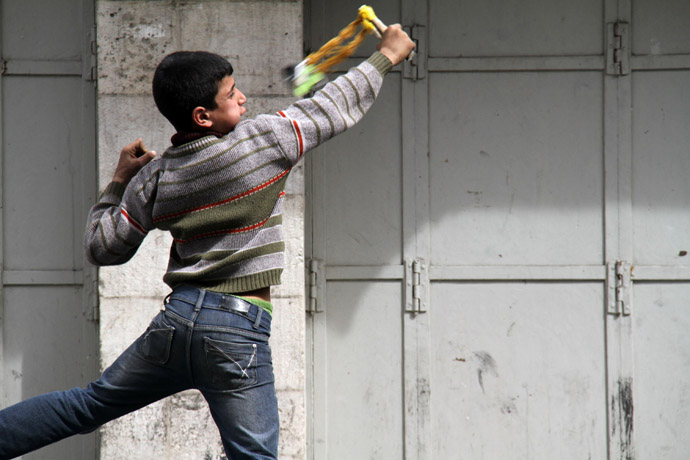 A Palestinian boy uses a slingshot to throw stones towards Israeli border policemen during clashes in central Hebron in the occupied West Bank (AFP Photo)