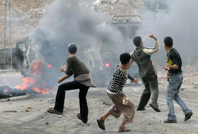 Palestinian boys throw rocks at an Israel army vehicule during an army operation in the refugee camp Al-Faraah, outside the West Bank City of Jenin (AFP Photo)