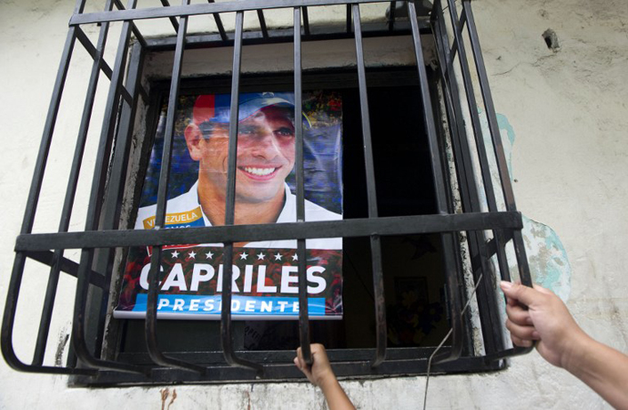 Supporters of Venezuelan opposition presidential candidate Henrique Capriles have a poster with his picture at their home in the Petare slum in Caracas on April 13, 2013. (AFP Photo / Raul Arboleda)