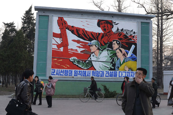 North Koreans stand in front of a political mural in Pyongyang. (AFP Photo / Pedro Ugarte)