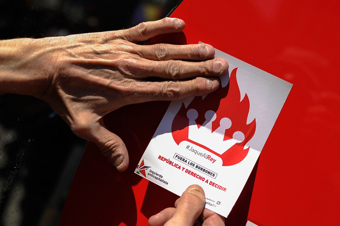 A man stick a sticker reading "Bourbon monarchy out, Republic and the right to decide" during a demonstration by Republicans in Madrid, on April 14, 2013 to commemorate the 82nd anniversary of the Second Republic (AFP Photo / Pedro Armestre) 