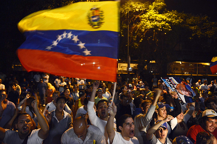Supporters of the Venezuelan Opposition leader Henrique Capriles wave national flag outside the place were he deliver a press conference in Caracas on April 15, 2013. (AFP Photo / Leo Ramirez)