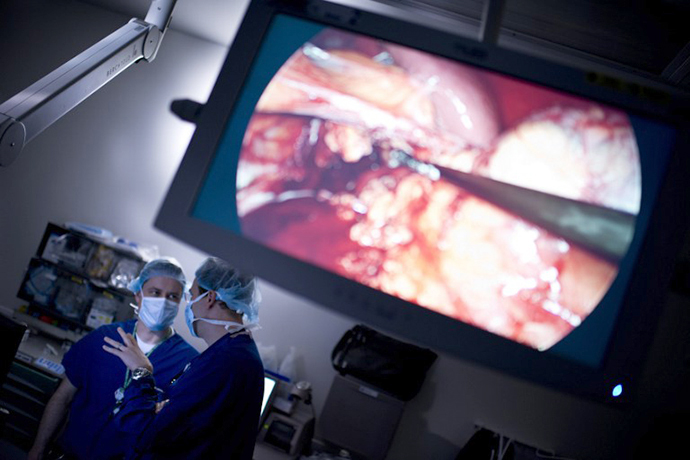Doctors talk while laparoscopic surgery is seen on a screen in the operating room during a kidney transplant. (AFP Photo / Brendan Smialowski)